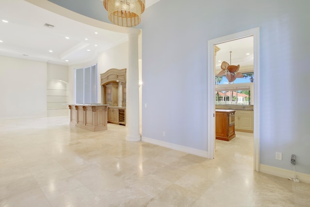 empty room featuring a raised ceiling, ornate columns, and ornamental molding