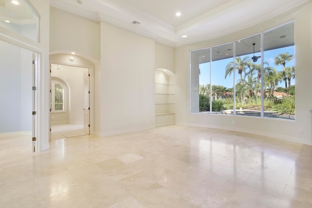 unfurnished room with built in shelves, a tray ceiling, and ornamental molding