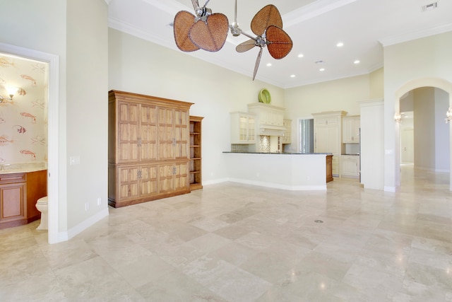 unfurnished living room with ceiling fan, a towering ceiling, and ornamental molding