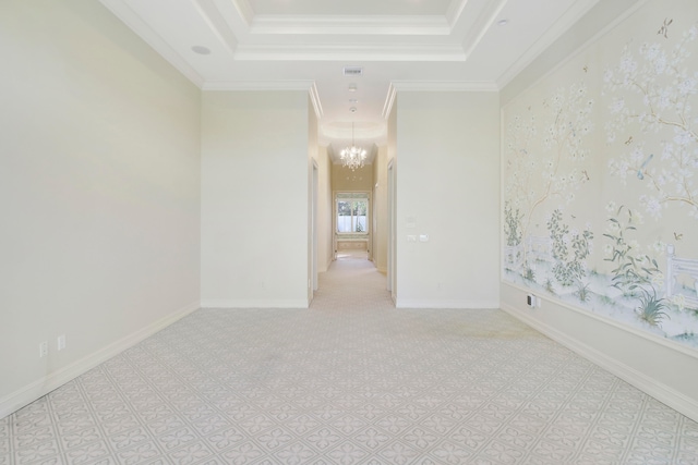 spare room with a chandelier, a tray ceiling, and ornamental molding