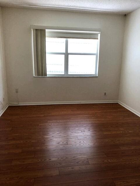 spare room with a textured ceiling, a wealth of natural light, and dark hardwood / wood-style flooring