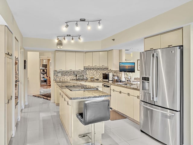 kitchen with cream cabinetry, light tile patterned floors, stainless steel appliances, and a kitchen island