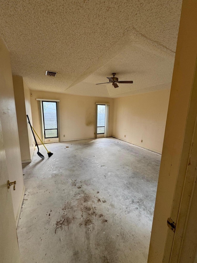 empty room featuring a wealth of natural light, ceiling fan, and a textured ceiling