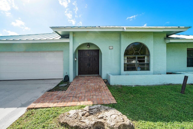 view of exterior entry featuring a garage and a lawn