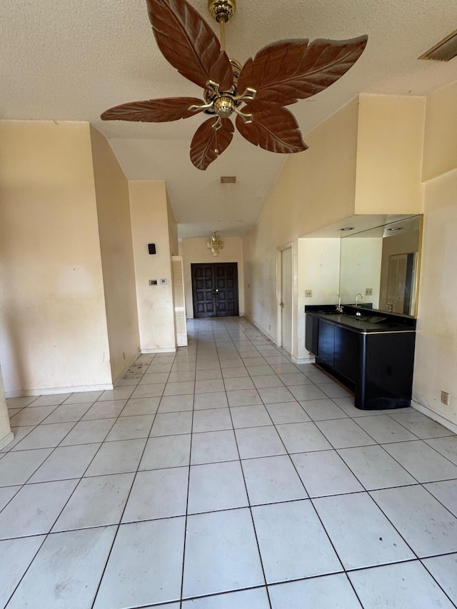 unfurnished living room with a textured ceiling, ceiling fan, and light tile patterned flooring