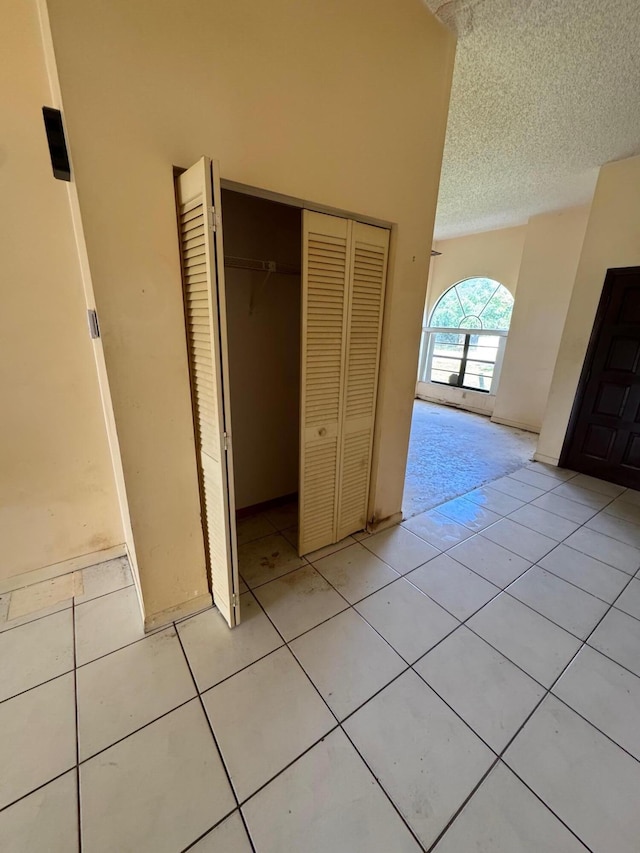 unfurnished bedroom featuring a closet, a textured ceiling, and light tile patterned floors