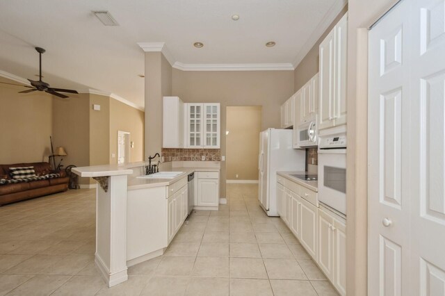 kitchen with a breakfast bar area, kitchen peninsula, sink, white cabinetry, and white appliances