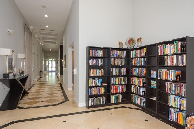 hall featuring tile patterned floors and a towering ceiling