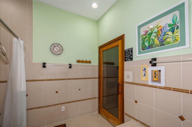 bathroom with tile walls, a shower with shower curtain, and tile patterned flooring