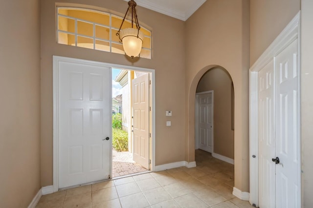 foyer entrance with ornamental molding and light tile patterned floors