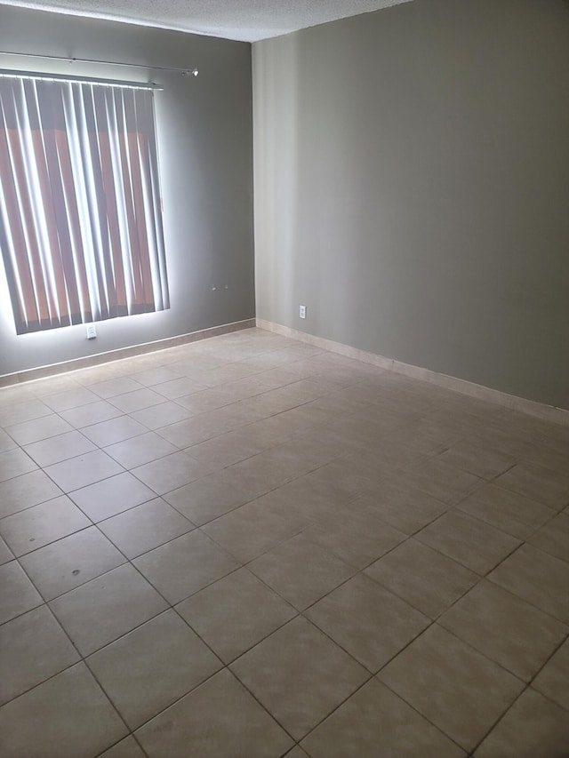 empty room with a textured ceiling and light tile patterned floors