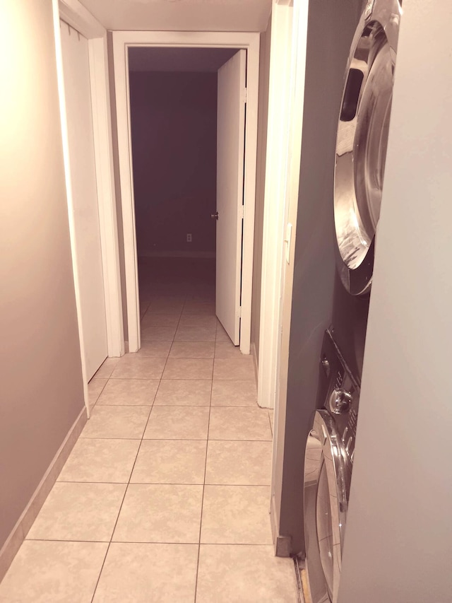 corridor with stacked washing maching and dryer and light tile patterned floors