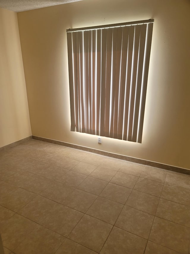 empty room featuring a textured ceiling and light tile patterned floors