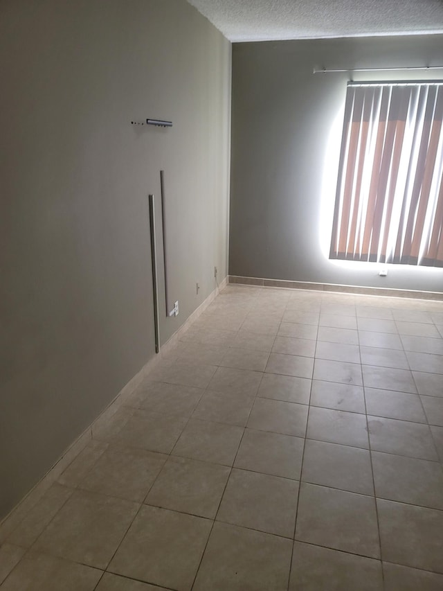 unfurnished room featuring a textured ceiling and light tile patterned floors