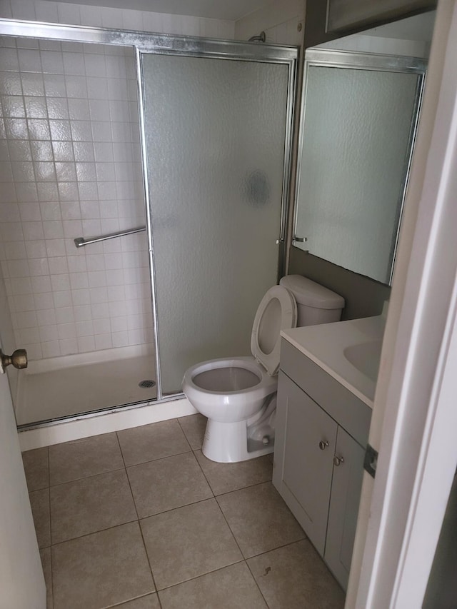 bathroom featuring vanity, walk in shower, toilet, and tile patterned floors