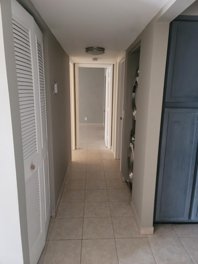 corridor with stacked washer / dryer and light tile patterned flooring