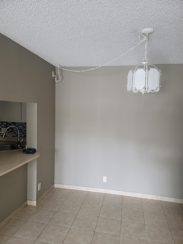 unfurnished dining area with light tile patterned floors, a textured ceiling, and sink