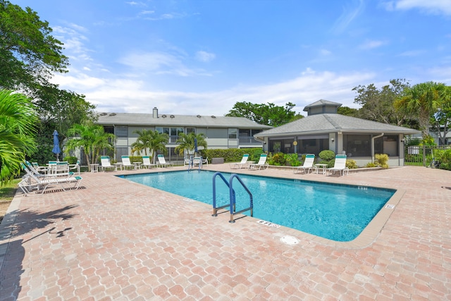 view of swimming pool with a sunroom and a patio