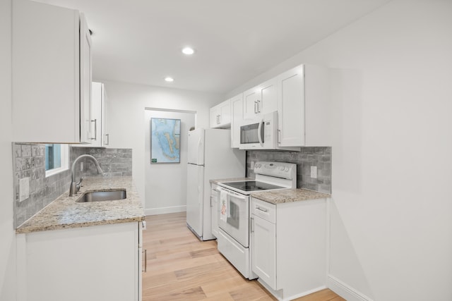 kitchen with light stone counters, sink, white cabinets, and white appliances