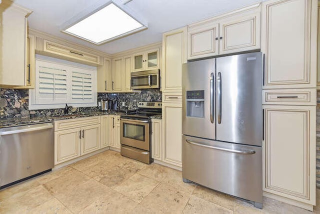 kitchen featuring cream cabinets, decorative backsplash, stainless steel appliances, and sink