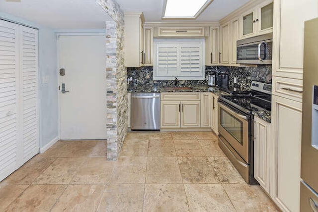 kitchen featuring appliances with stainless steel finishes, sink, backsplash, and cream cabinetry