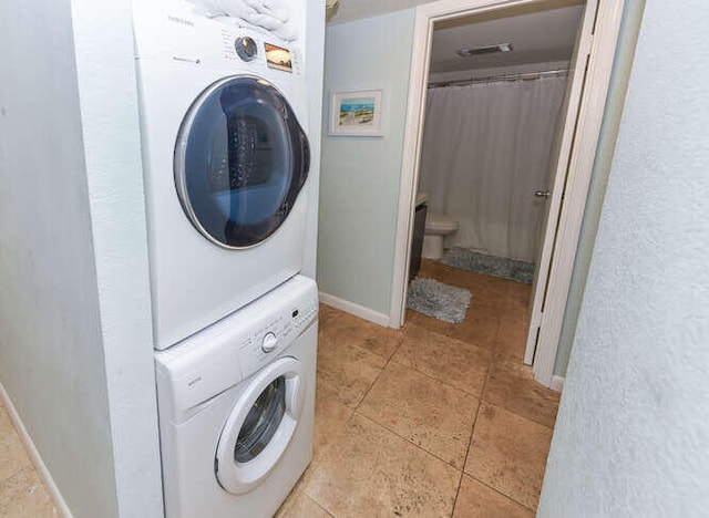 clothes washing area with stacked washing maching and dryer