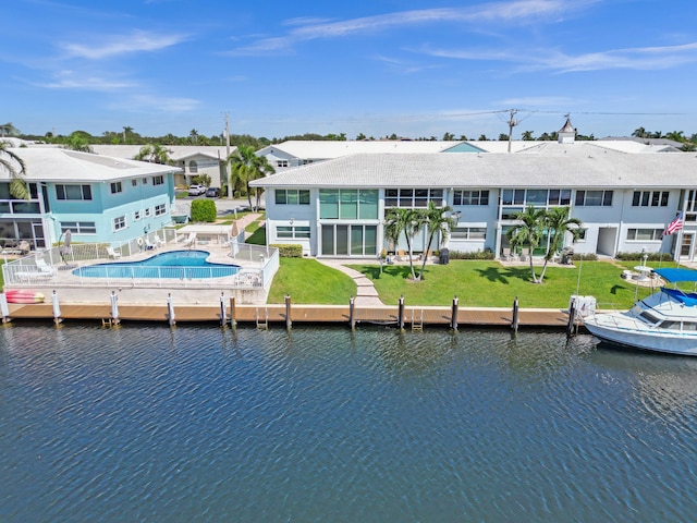 back of property with a patio area, a community pool, a yard, and a water view