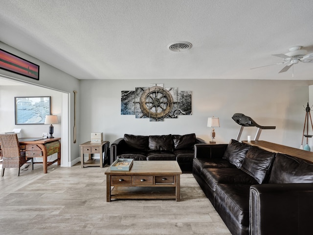 living room with light hardwood / wood-style floors, a textured ceiling, and ceiling fan