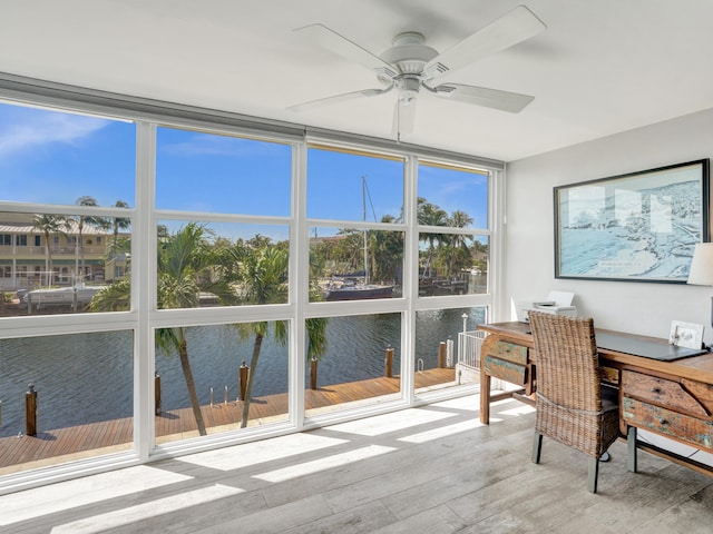 office area with a wall of windows, a water view, light wood-type flooring, and ceiling fan