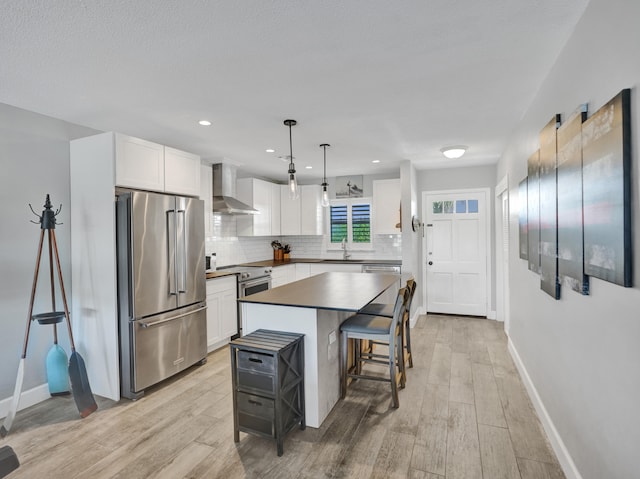 kitchen featuring light wood-type flooring, a kitchen island, hanging light fixtures, white cabinetry, and stainless steel appliances