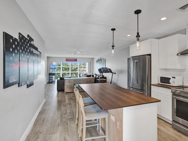 kitchen with a breakfast bar area, a kitchen island, white cabinets, and stainless steel appliances