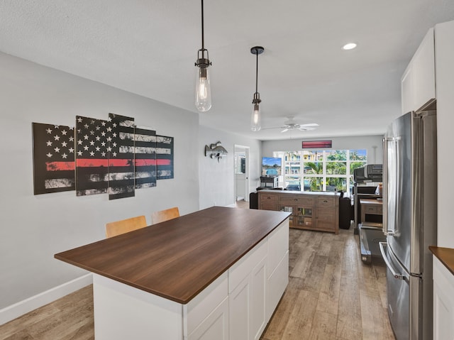 kitchen featuring white cabinetry, ceiling fan, light wood-type flooring, and stainless steel refrigerator