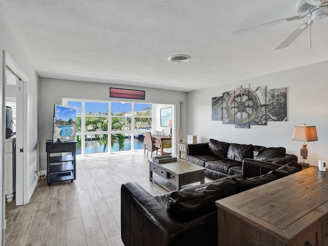 living room with light hardwood / wood-style floors, a textured ceiling, and ceiling fan