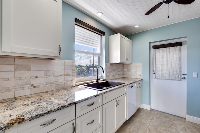 kitchen featuring dishwasher, sink, backsplash, white cabinets, and light stone counters