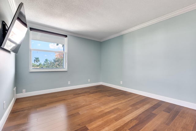 empty room with ornamental molding, a textured ceiling, and wood-type flooring