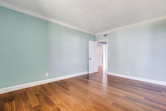 spare room with crown molding, a textured ceiling, and wood-type flooring