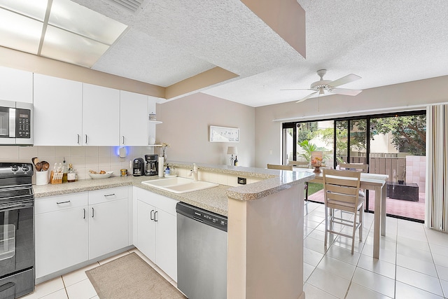 kitchen featuring sink, appliances with stainless steel finishes, kitchen peninsula, and a textured ceiling