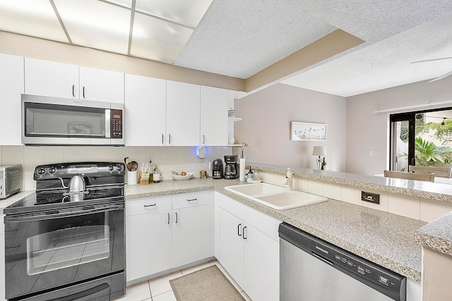 kitchen with kitchen peninsula, light tile patterned floors, a textured ceiling, sink, and stainless steel appliances