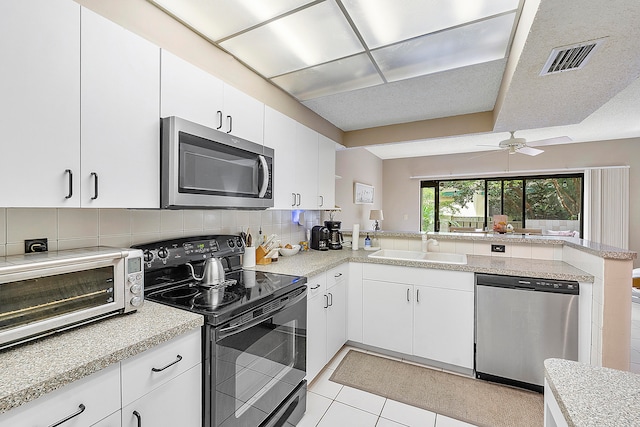 kitchen with white cabinetry, kitchen peninsula, stainless steel appliances, and tasteful backsplash