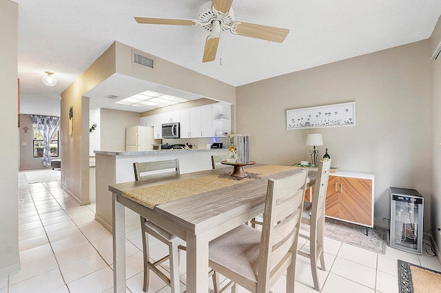 tiled dining room featuring a textured ceiling, heating unit, and ceiling fan