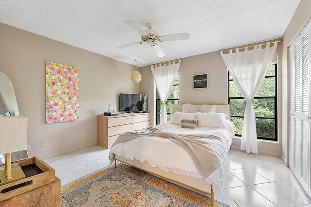 tiled bedroom featuring a closet, ceiling fan, and a textured ceiling