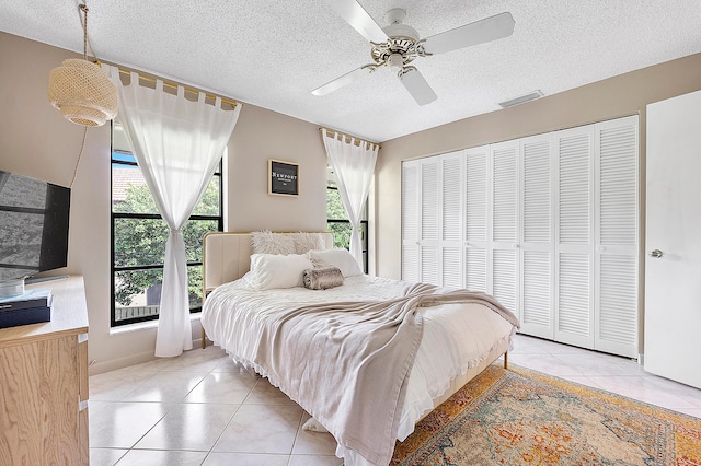 tiled bedroom featuring a closet, a textured ceiling, and ceiling fan