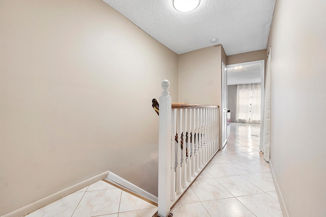 hall featuring a textured ceiling and light tile patterned floors