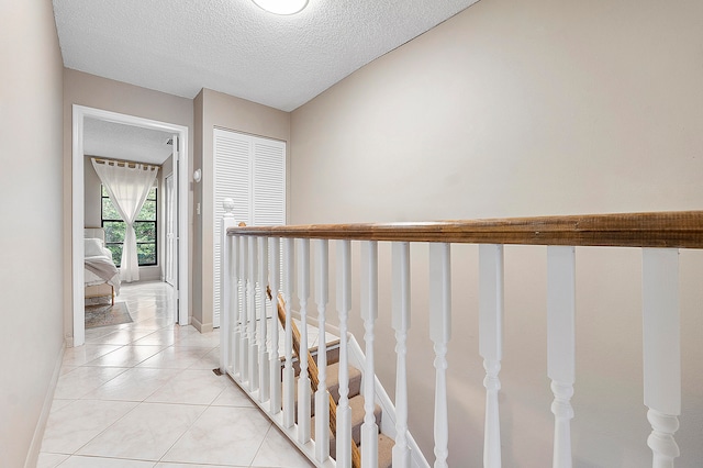 hallway with a textured ceiling and light tile patterned floors