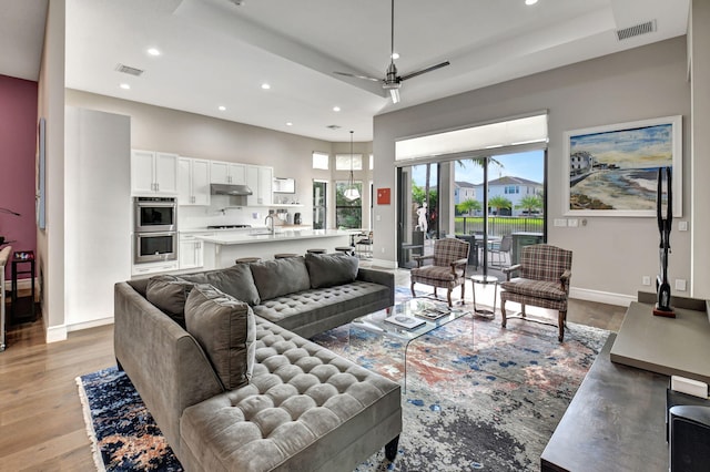 living room featuring sink, light hardwood / wood-style flooring, and ceiling fan