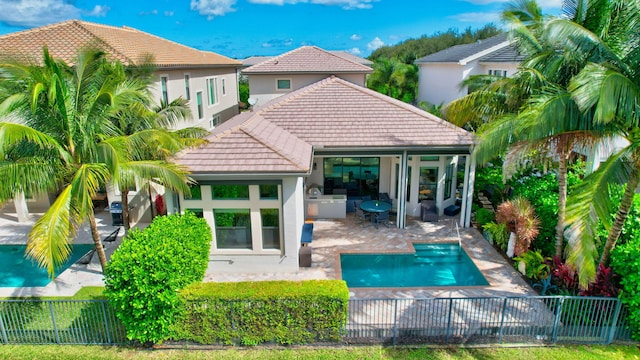 rear view of house with a fenced in pool and a patio area