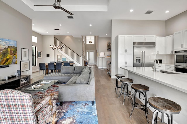 living room with light hardwood / wood-style floors, sink, and ceiling fan