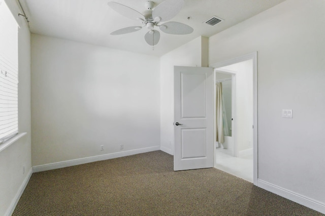 empty room with ceiling fan and dark colored carpet