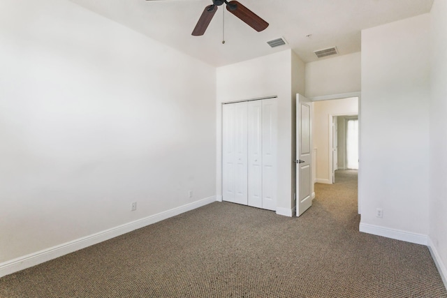 unfurnished bedroom with ceiling fan, a closet, and dark carpet