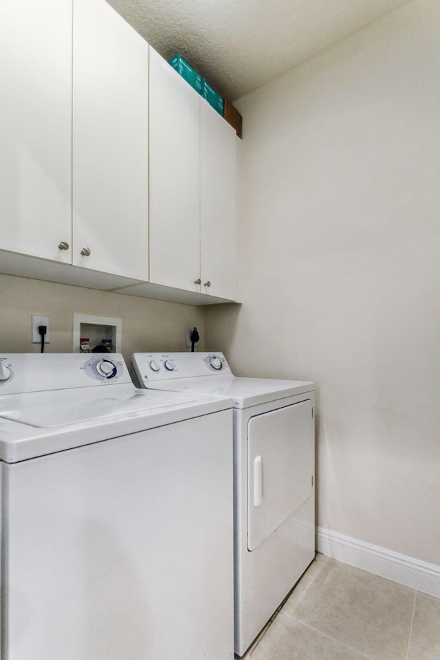 washroom featuring a textured ceiling, light tile patterned flooring, cabinets, and washer and dryer